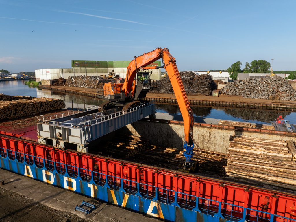 Overslagkraan lost boomstammen uit het ruim van een schip